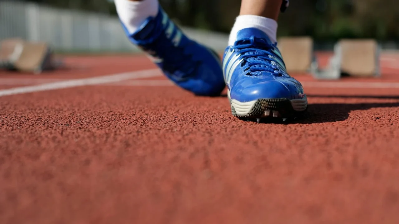 Blue running shoes on a red athletics track