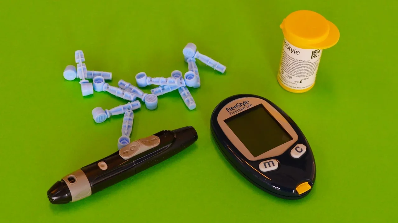 A glucose meter, lancing device and lancets on a green surface