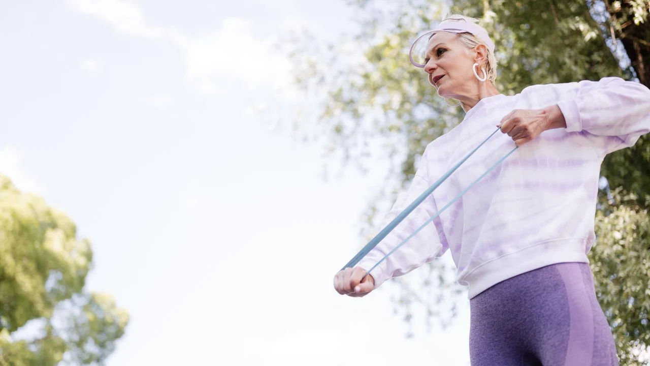 An older adult exercising outdoors with a resistance band