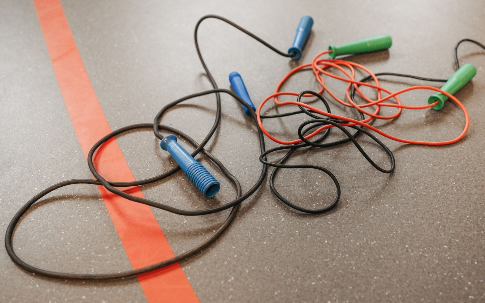 Tangled jump ropes on a gym floor highlighting fitness and exercise equipment.